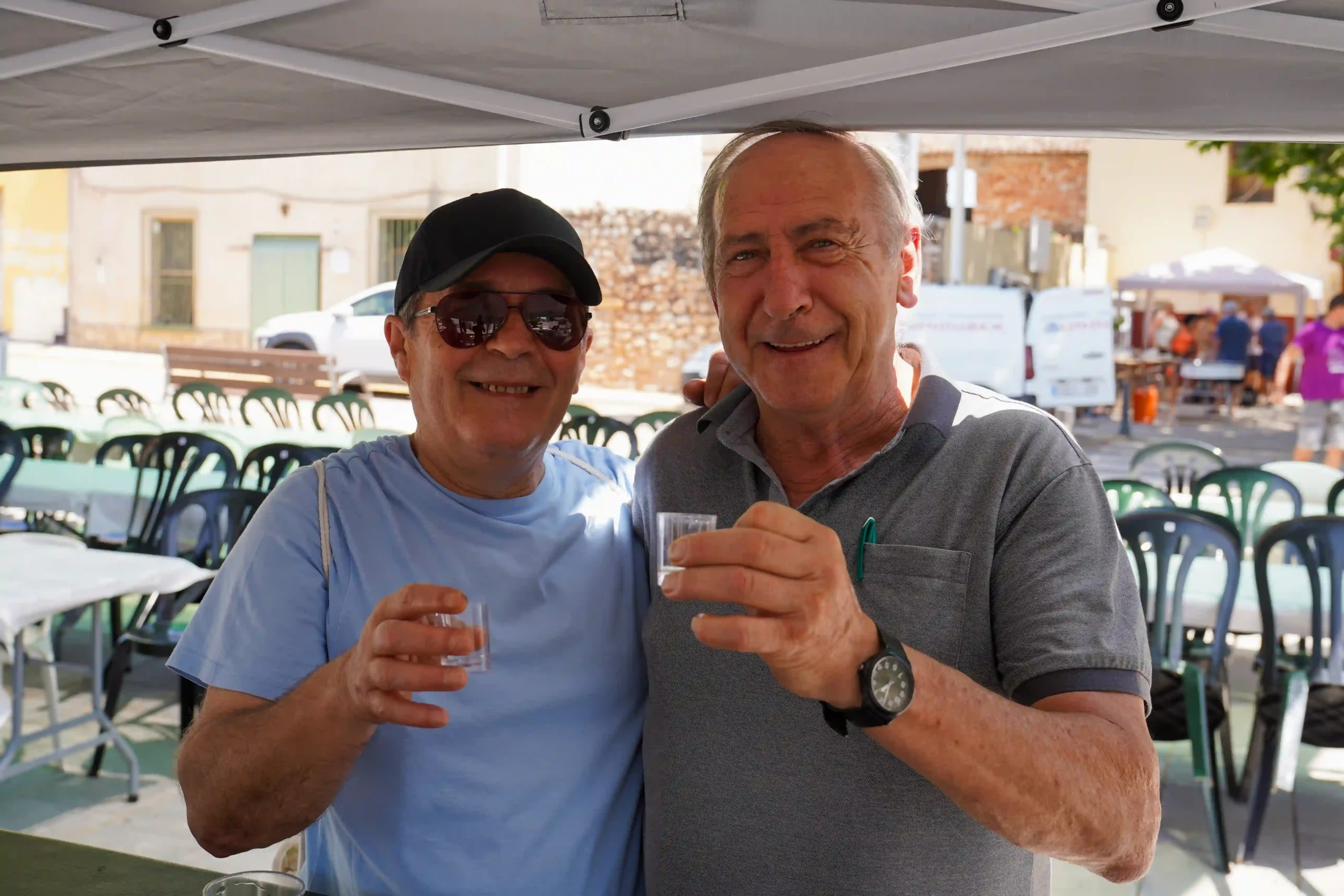 Dos hombres en la barra compartiendo un trago de casalla durante la Romería a la Mare de Déu del Mondúver 2025 en Marxuquera