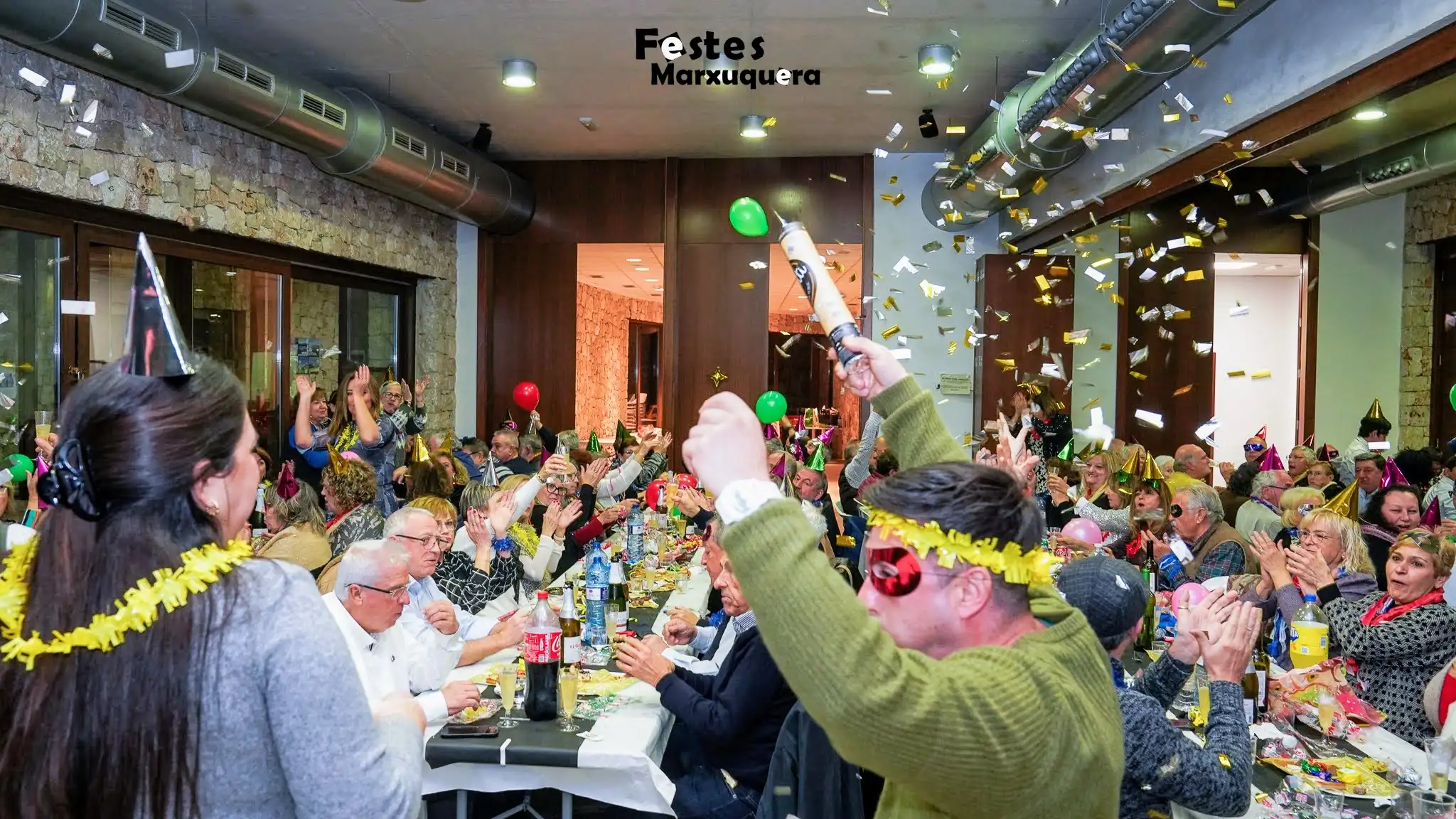 Vecinos de Marxuquera celebrando las campanadas con confeti, brindis y cotillón en la entrada de 2025