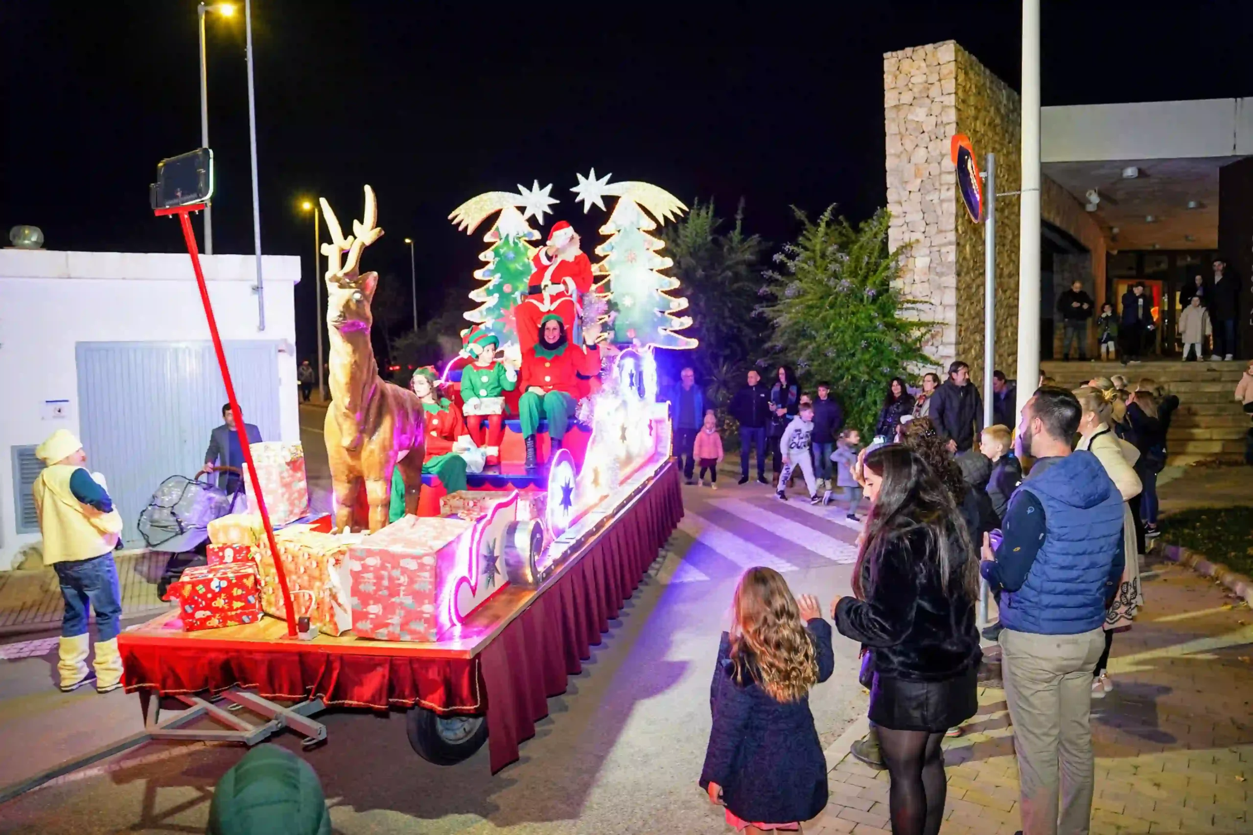 Papá Noel y sus elfos saludando desde la carroza decorada e iluminada en la cabalgata de Navidad en Marxuquera