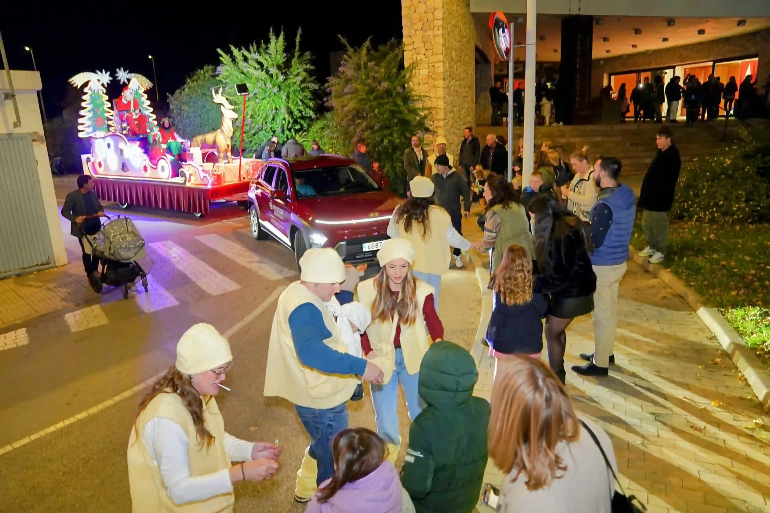 Voluntarios reparten caramelos mientras la carroza de Papá Noel desfila ante el público en el Centro Social