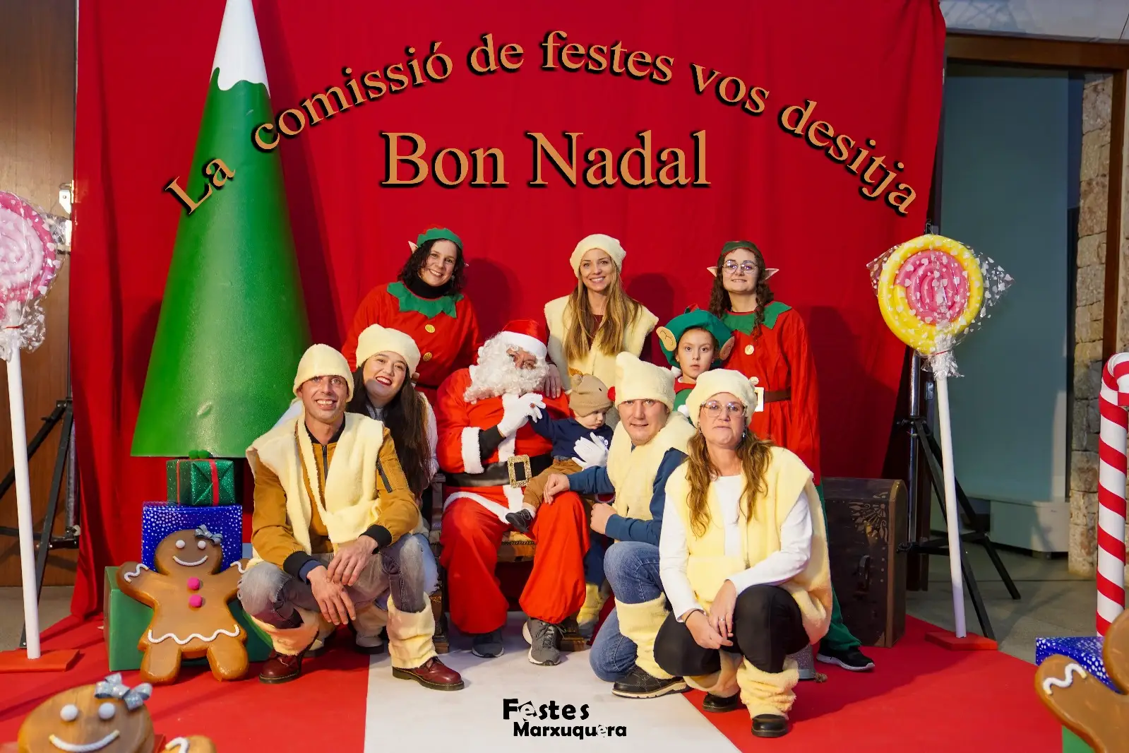 Foto de la comisión de festes de Marxuquera posando con Papá Noel en el decorado navideño del Centre Social
