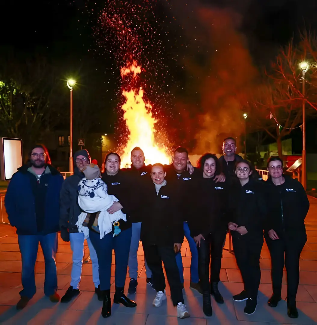 Comisión de Marxuquera posando de noche frente a la hoguera encendida de Sant Antoni 2025