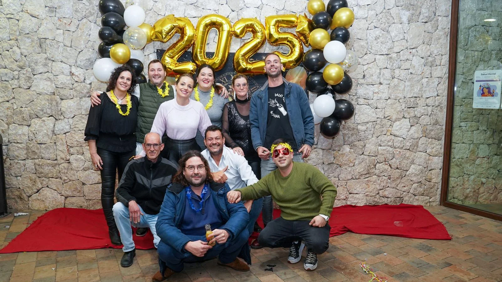 Miembros de la comisión de festes de Marxuquera posando en el photocall decorado con globos dorados durante la Nochevieja 2024