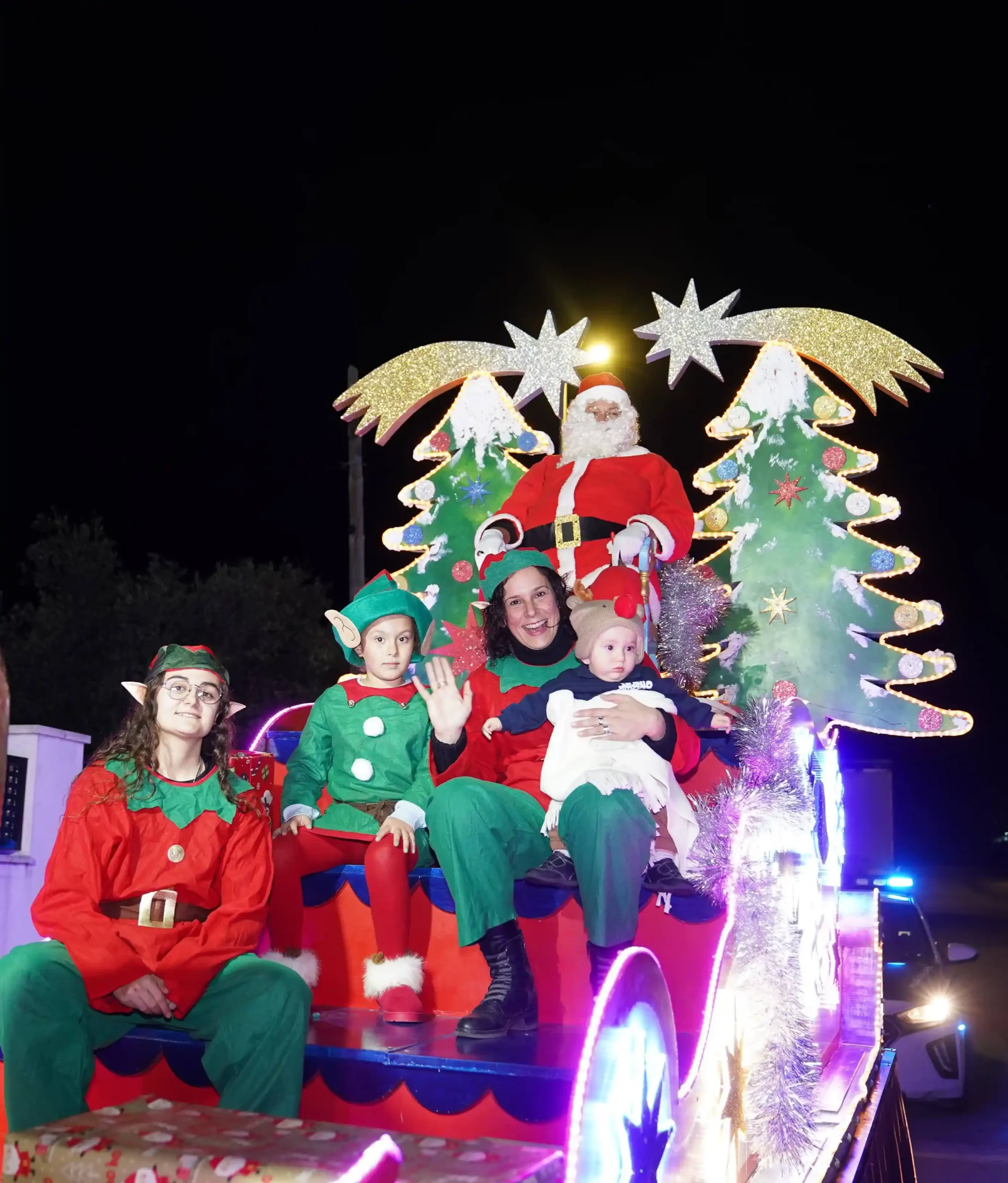 Papá Noel y sus elfos en la carroza iluminada durante el desfile navideño por las calles de Marxuquera