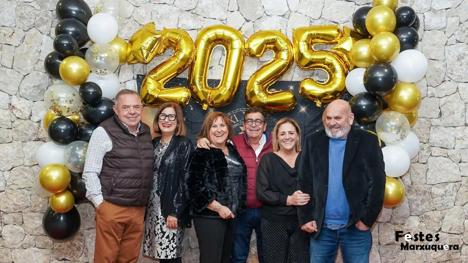 Grupo de amigos con disfraces y globos 2025 celebrando la Nochevieja 2024 en el decorado festivo de Marxuquera