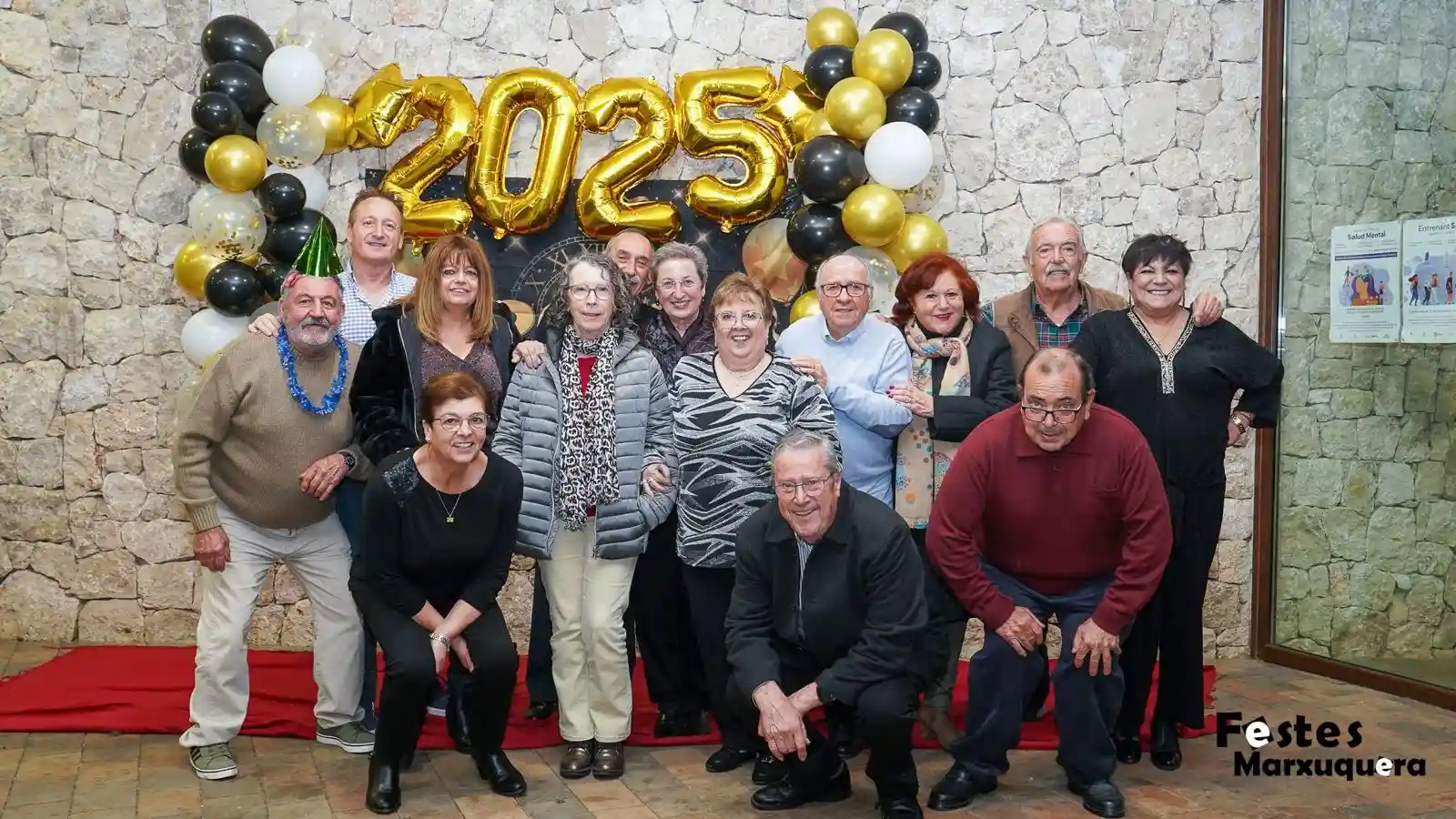Grupo de personas mayores posa en el photocall con decoración navideña durante la fiesta de fin de año en el Centre Social