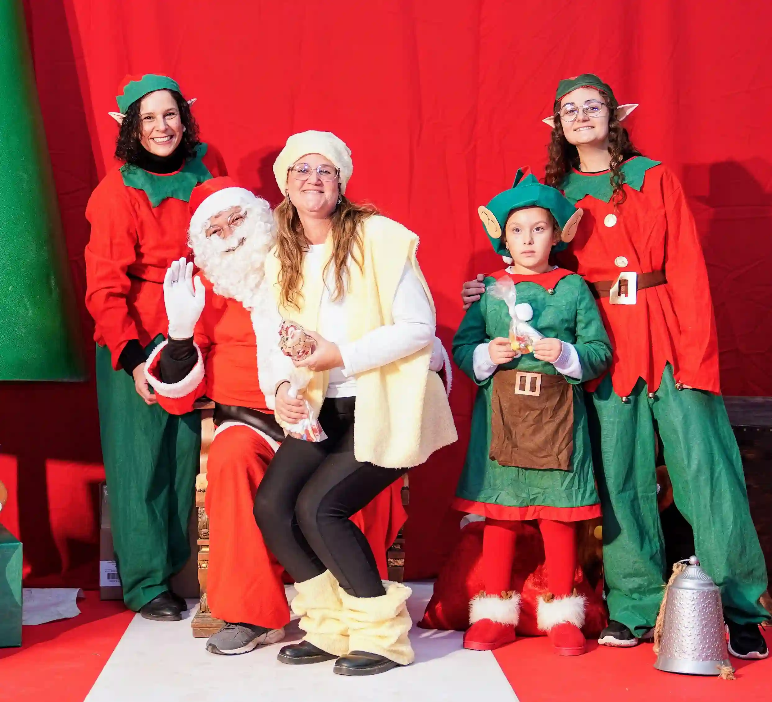 Papá Noel posando con una pastoreta y elfos navideños durante la entrega de regalos en Marxuquera