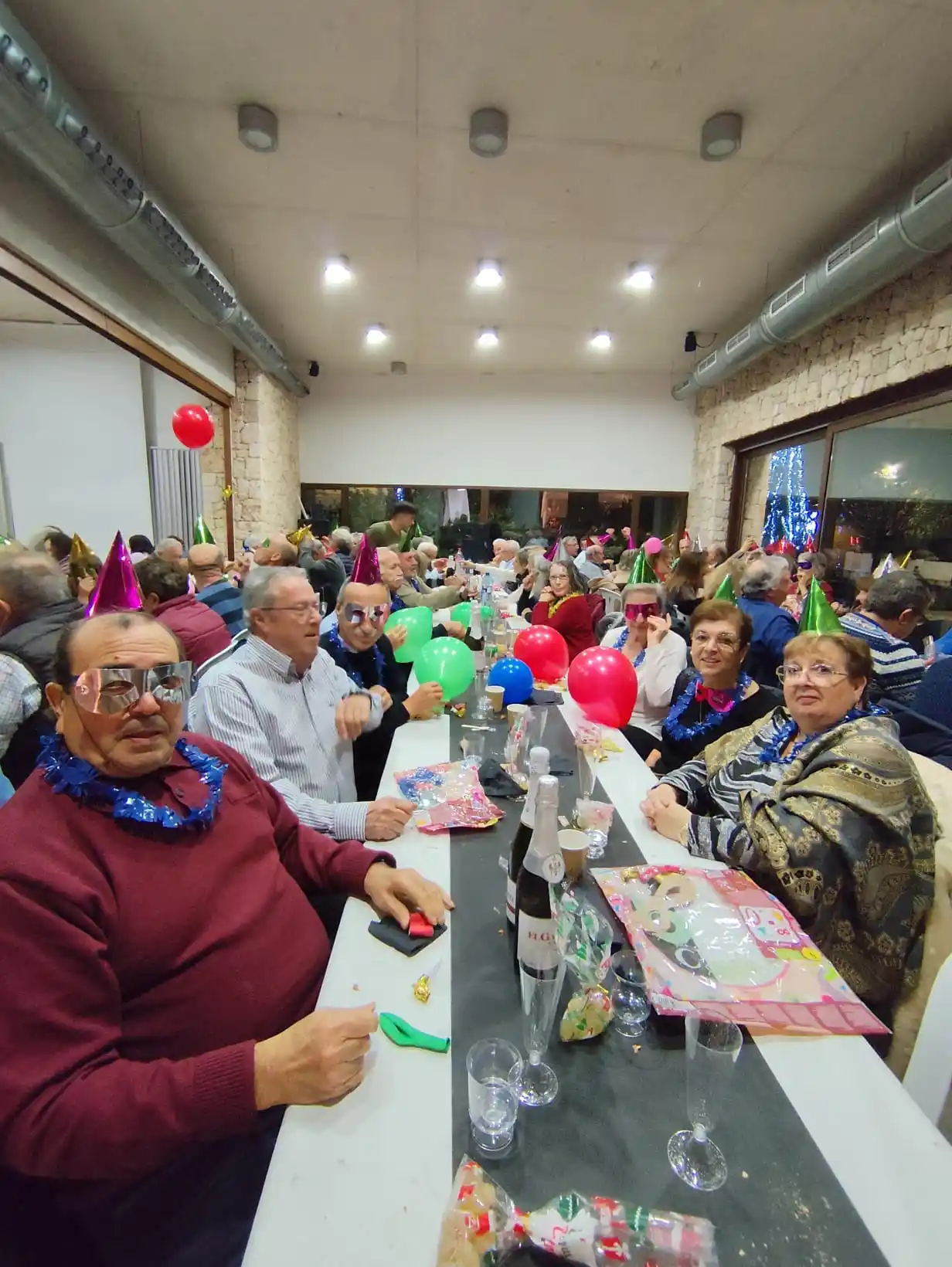 Vecinos compartiendo mesa, gorros de fiesta y cotillón durante la celebración de Fin de Año en Marxuquera