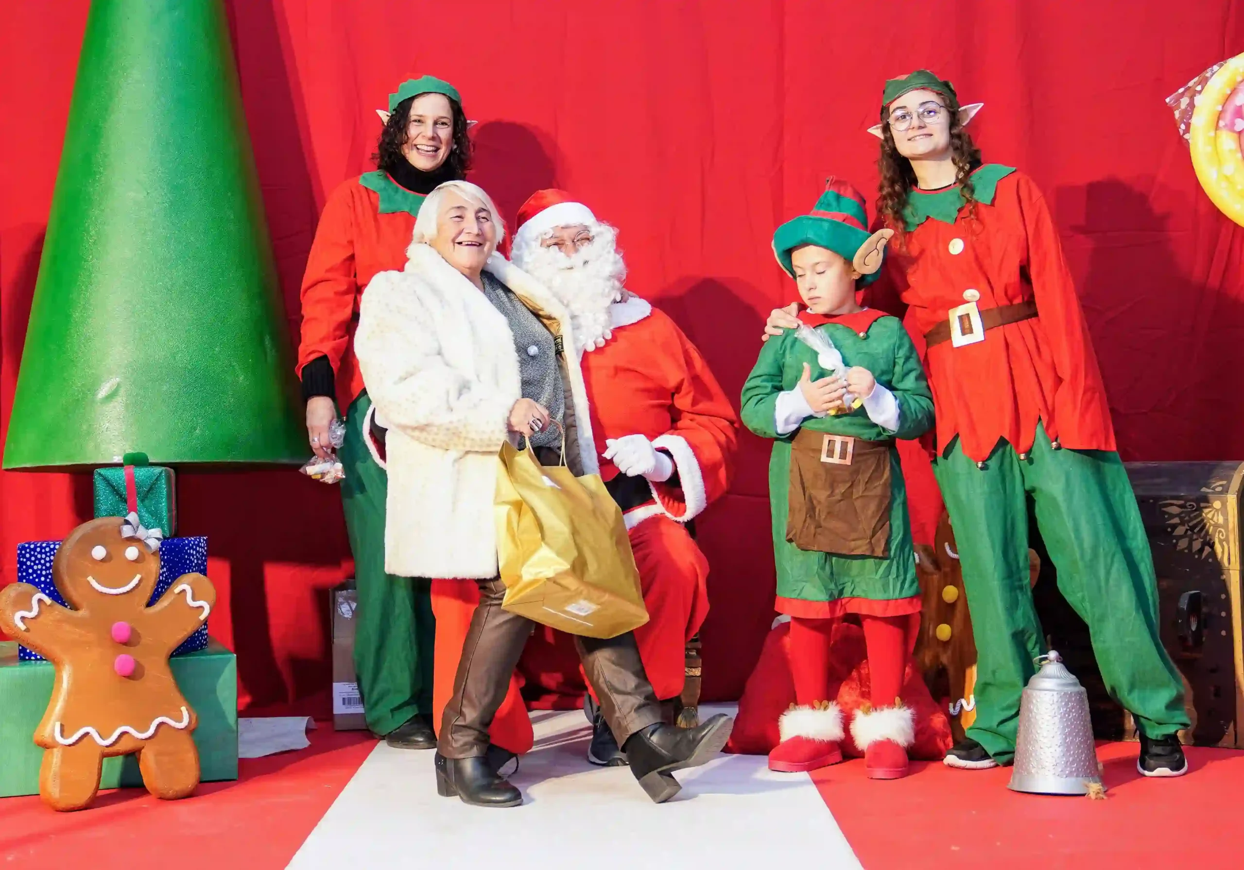 Foto entrañable de una señora junto a Papá Noel y elfos navideños en el decorado del Centro Social