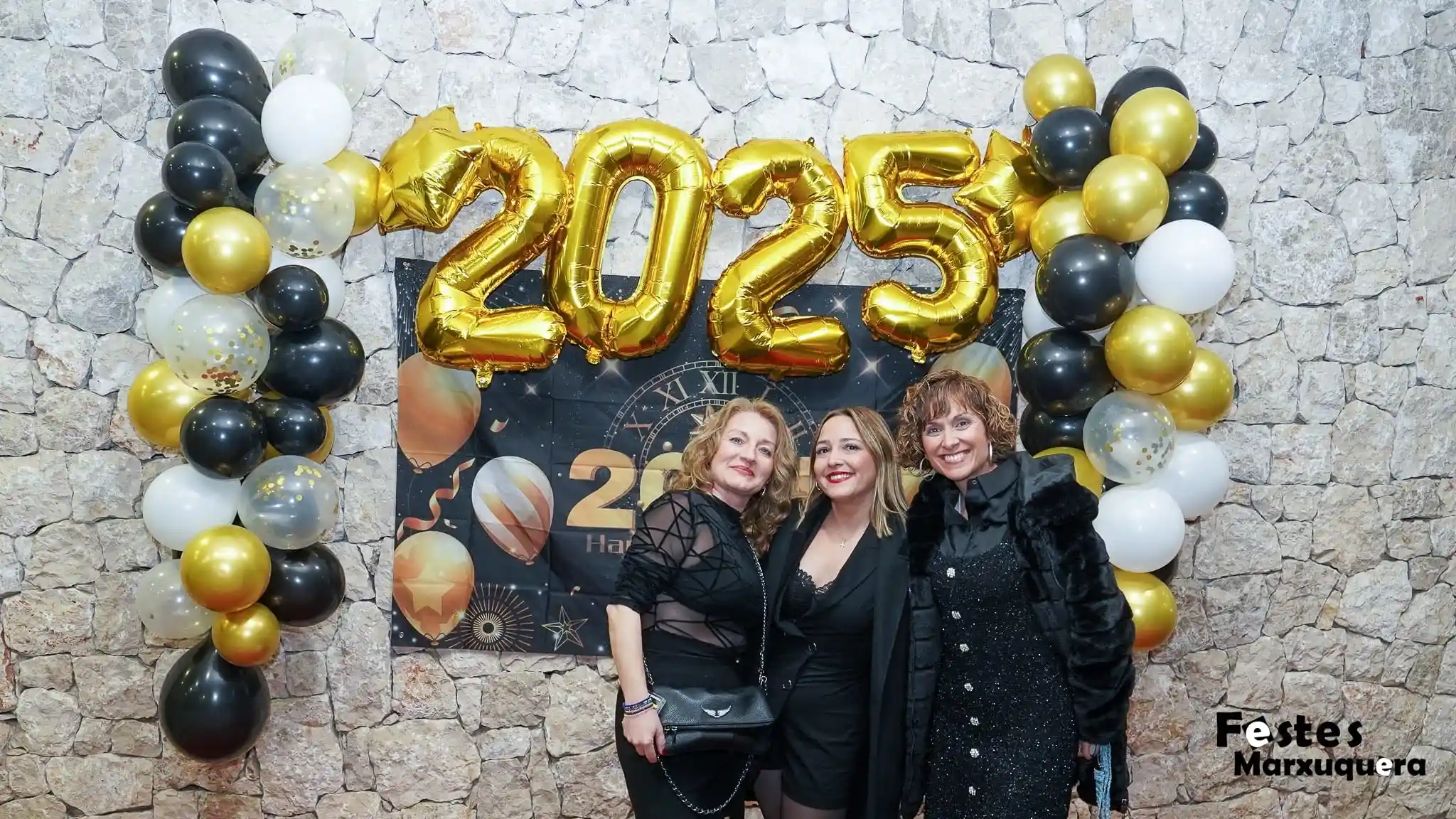 Mujeres con vestidos negros posan alegres bajo los globos 2025 durante la fiesta de fin de año