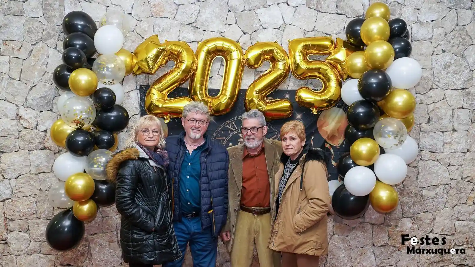 Dos hombres y dos mujeres posan con estilo frente a los globos dorados 2025 durante la fiesta de fin de año