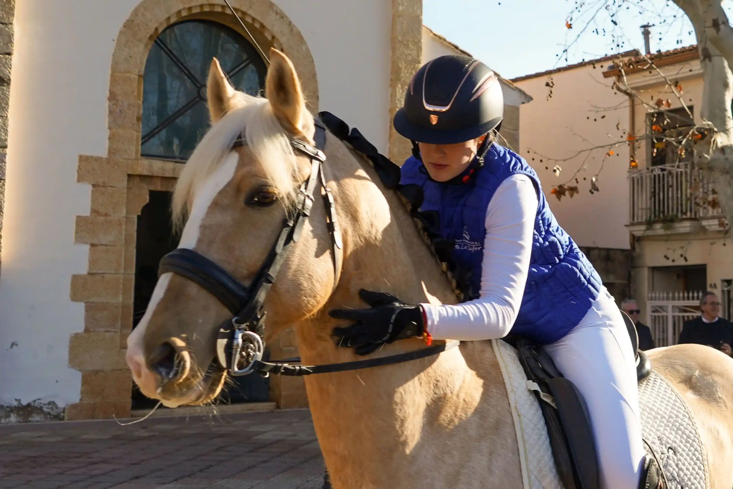 Jinete acariciando a su caballo junto a la iglesia durante la bendición de Sant Antoni 2025 en Marxuquera.