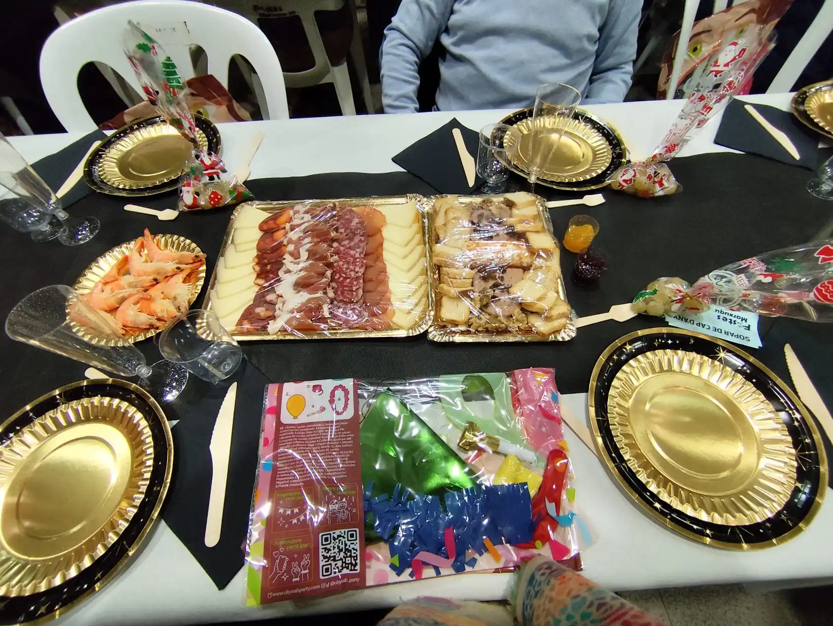 Detalle de la mesa decorada con entrantes, vajilla dorada y cotillón en la fiesta de Nochevieja 2024 en Marxuquera