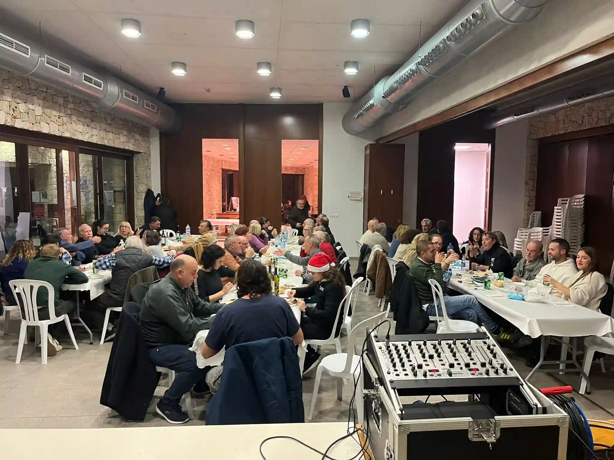 Vista del comedor con vecinos celebrando y equipo de sonido en primer plano