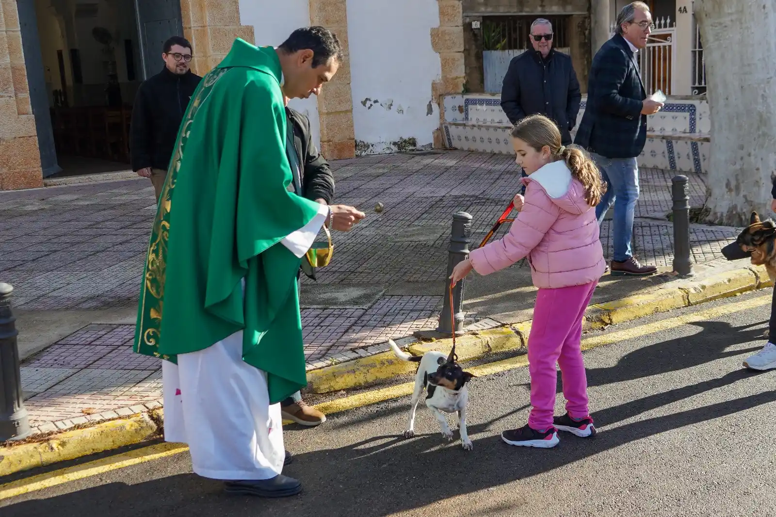 Niña con un perro pequeño en la bendición de animales frente a la iglesia en Sant Antoni 2025.