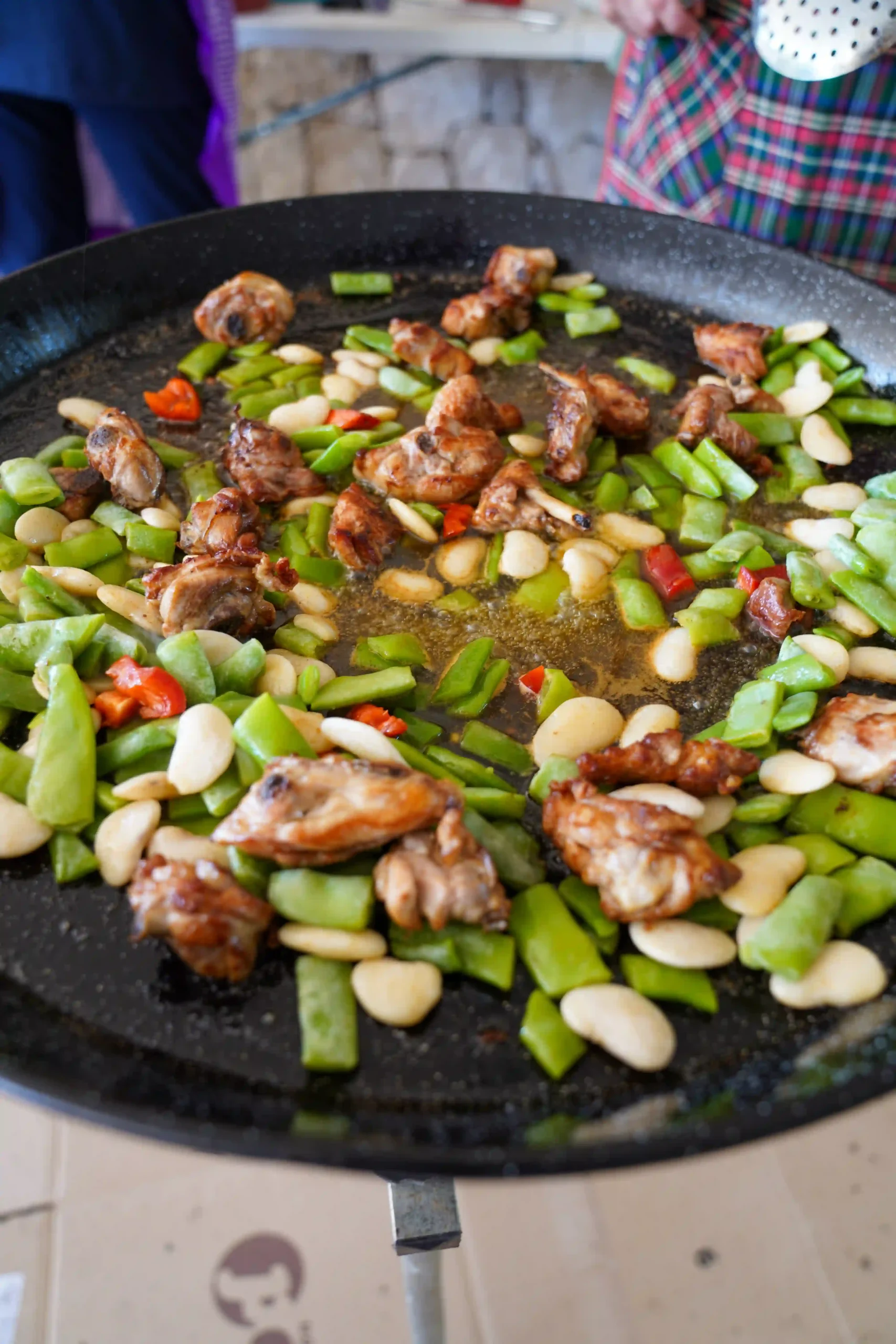 Paella cocinándose con carne, garrofón, pimiento rojo y judía verde durante la Romería a la Mare de Déu del Mondúver 2025 en Marxuquera
