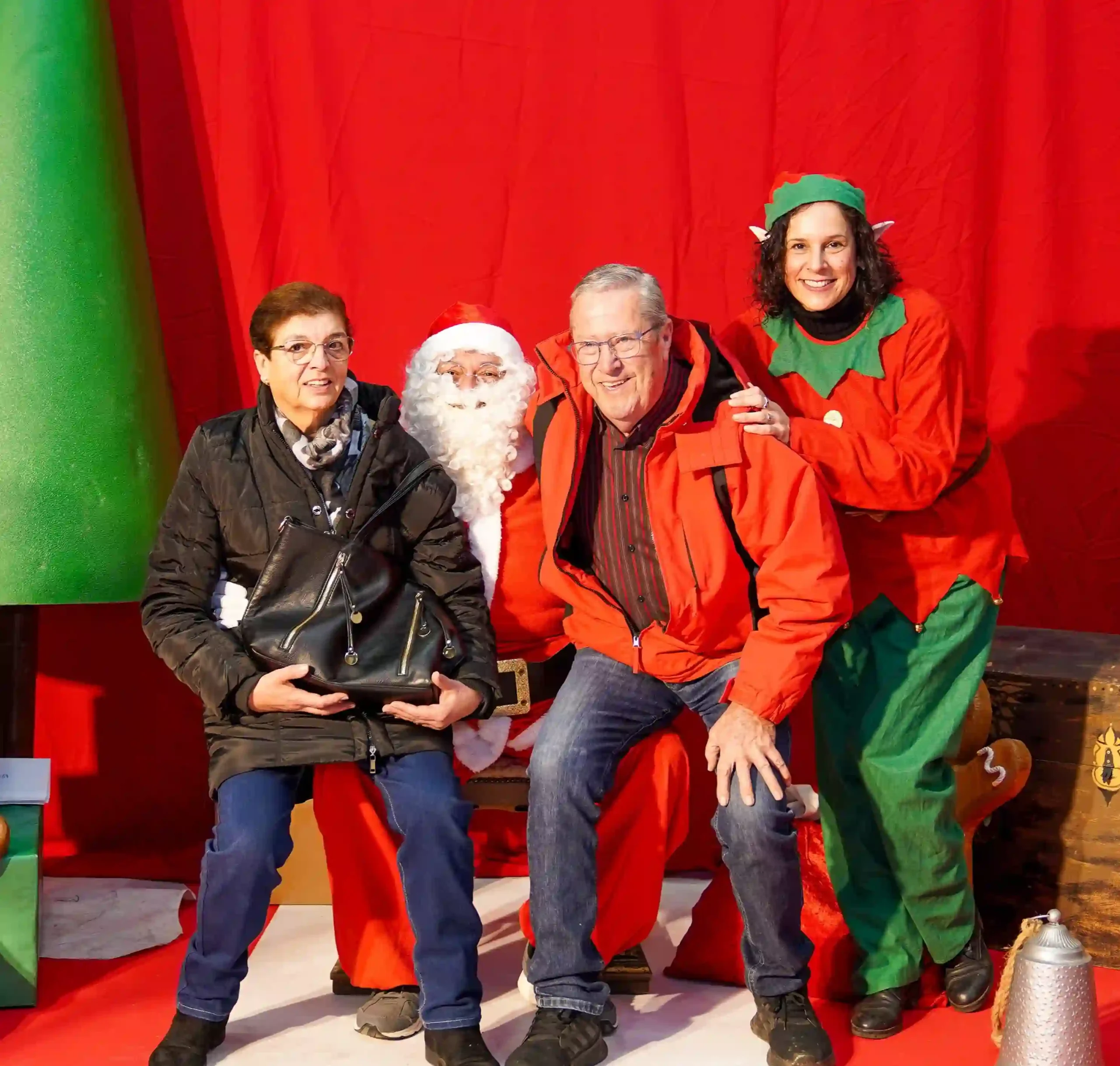 Una pareja mayor posa junto a Papá Noel y una elfa durante la visita navideña 2024