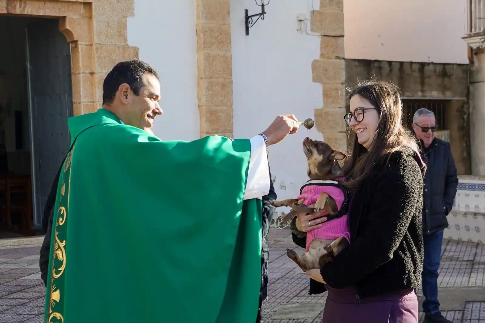 Perra con jersey rosa en brazos de su dueña recibiendo la bendición en Sant Antoni 2025.