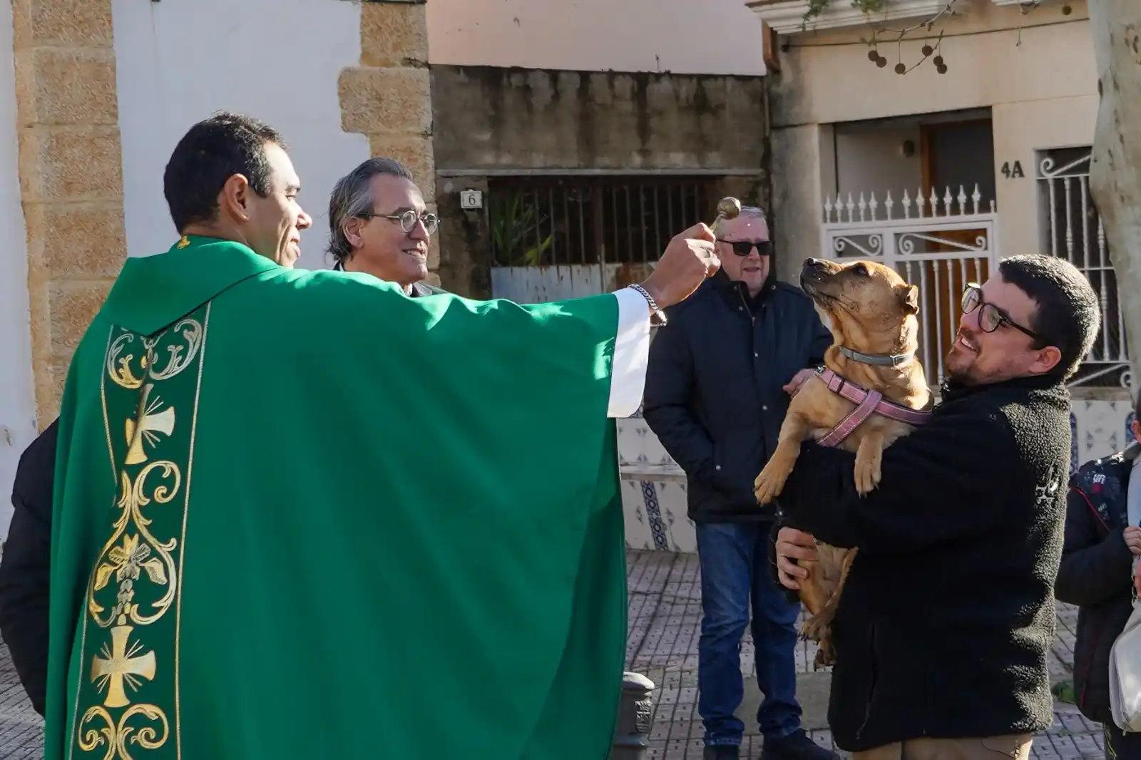 Perro en brazos de su dueño recibiendo la bendición del cura en Sant Antoni 2025 en Marxuquera.