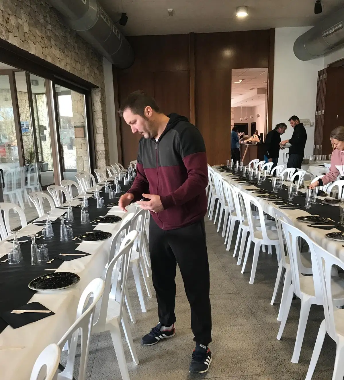 Voluntarios montando las mesas con vajilla negra y dorada para la cena de Nochevieja 2024 en el Centre Social de Marxuquera