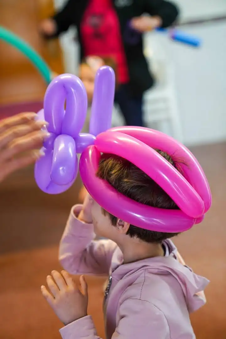Niña jugando con un globo en forma de corona en el taller infantil de Carnestoltes 2025 en Marxuquera