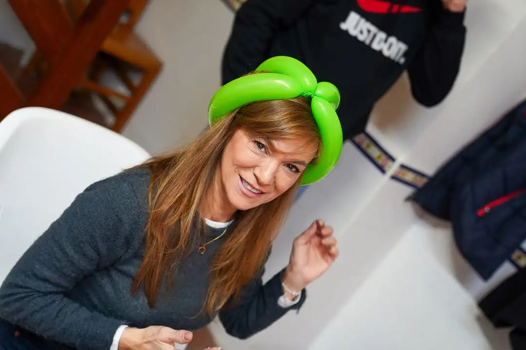 Mujer participando en el taller de globoflexia con un globo verde en el Carnaval 2025 en Marxuquera