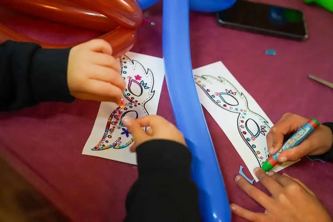 Niños creando máscaras y jugando con globos en el taller infantil de Carnavales 2025 en Marxuquera